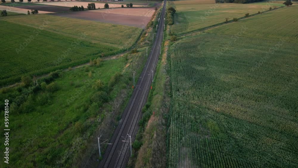 Aerial view of railway in countryside area at sunset. Railroad near agricultural fields Aerial view of railway in countryside area at sunset. Railroad near agricultural fields