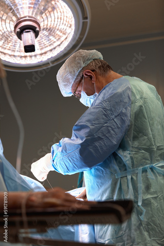 Surgeon face in operating room, stressful operation, surgeon performs operation in modern operating room with activity life support devices and light lamps, life saving, inoperable sarcoma. photo