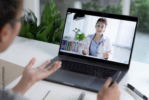Young Asian woman have video call with doctor at home. Female patient talk consult with physician online on webcam conference on computer.