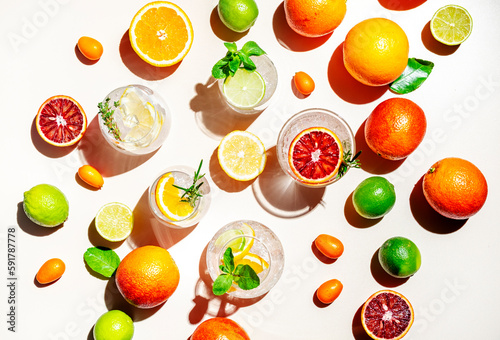 Gin tonic citrus and herb cocktails set  top view. Assortment of summer drinks for cocktail party. Light beige background  bright fruits  hard light  shadow pattern