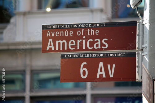 Photography Avenue of the Americas 6 Av brown traffic sign in New York between the skyscrape