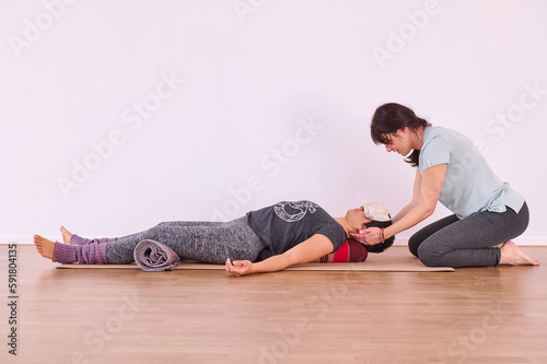 A yoga teacher holding the head of a girl to correct their posture