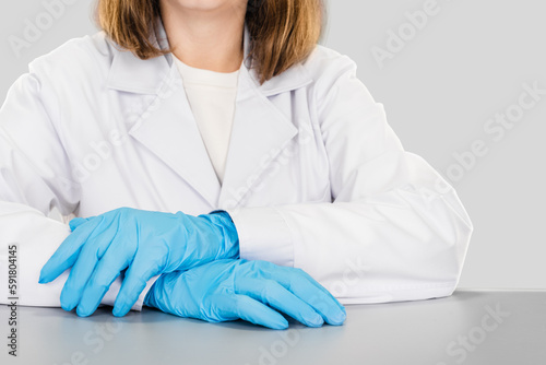 Closeup photo of a female pharmacist doctor in uniform posing on studio gray background