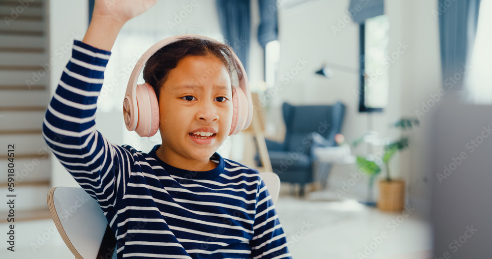 Asian toddler girl with sweater wear headphone sit front of desk with notepad use magic pen focus on writing do homework, finger counting number math online learning course from laptop at home. Asian toddler girl with sweater wear headphone sit front of desk with notepad use magic pen focus on writing do homework, finger counting number math online learning course from laptop at home.