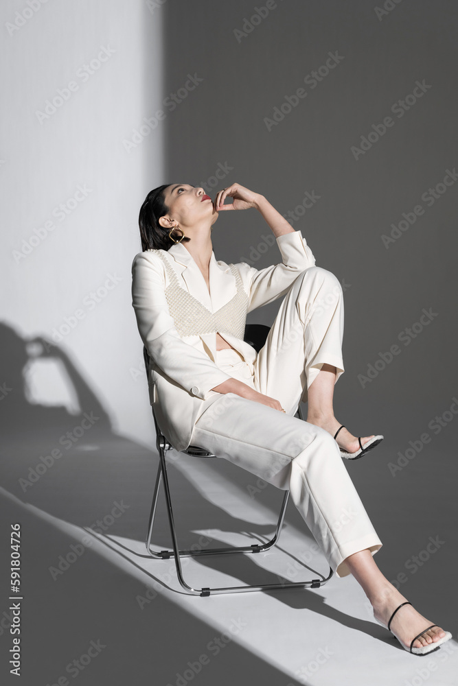 Fashionable young woman posing on chair Fashionable young woman posing on chair