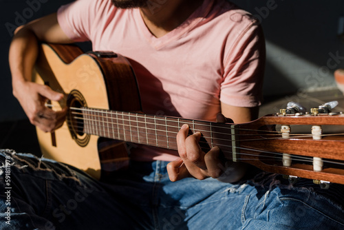 latin man playing acoustic guitar sitting on floor in living room at Sunny hard light on Stylish Loft Apartment in Mexico Latin America  hispanic people