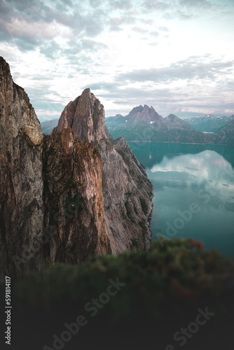 Vertical breathtaking view high mountain peak under a cloudy sky above a lake