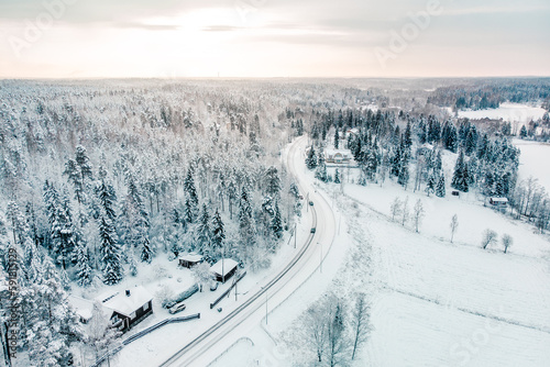 Aerial shot of a landscape covered with snowy pine forests and a village in winter © Kasper Garam/Wirestock Creators