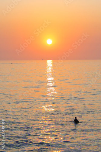 Vertical shot of a surfer in the beautiful sea at sunset in San Clemente, CA, USA photo