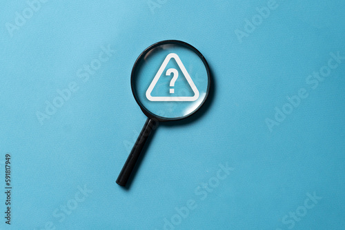 top view on a black magnifying glass with a question mark alarm, flat lay