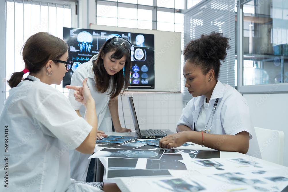 Group of female medical scientists meeting in brain research lab by monitor showing MRI, CT scans brain images. Group of doctors discuss treatment for brain patients, showing images on monitor Group of female medical scientists meeting in brain research lab by monitor showing MRI, CT scans brain images. Group of doctors discuss treatment for brain patients, showing images on monitor