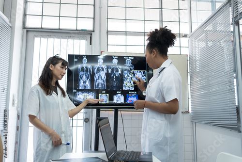 Group of female medical scientists meeting in brain research lab by monitor showing MRI, CT scans brain images. Group of doctors discuss treatment for brain patients, showing images on monitor photo