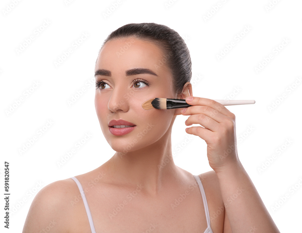 Woman applying foundation on face with brush against white background Woman applying foundation on face with brush against white background