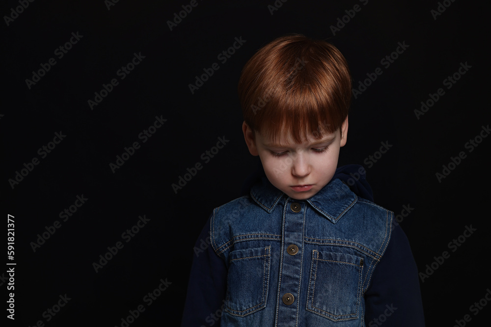 Upset boy on black background, space for text. Children's bullying Upset boy on black background, space for text. Children's bullying
