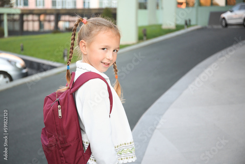 Cute little girl with backpack on city street. Space for text