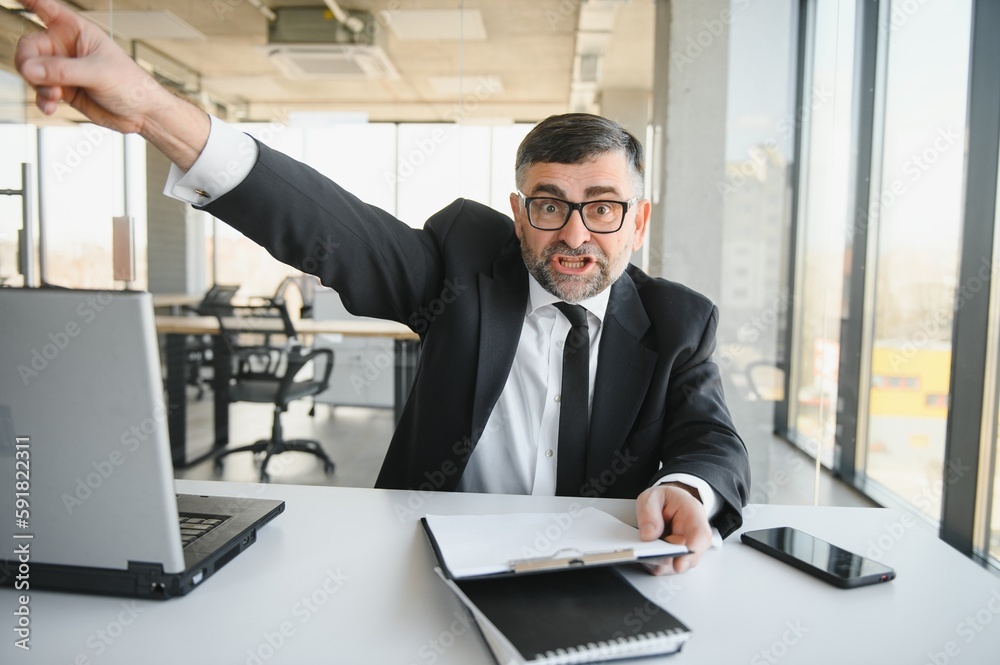 Angry businessman with too much work in office Angry businessman with too much work in office