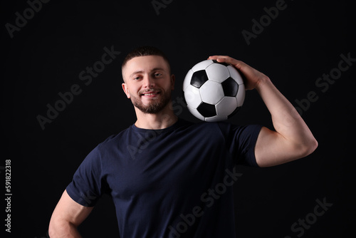 Athletic young man with soccer ball on black background © New Africa