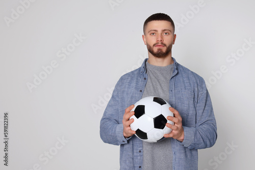 Athletic young man with soccer ball on light grey background. Space for text © New Africa