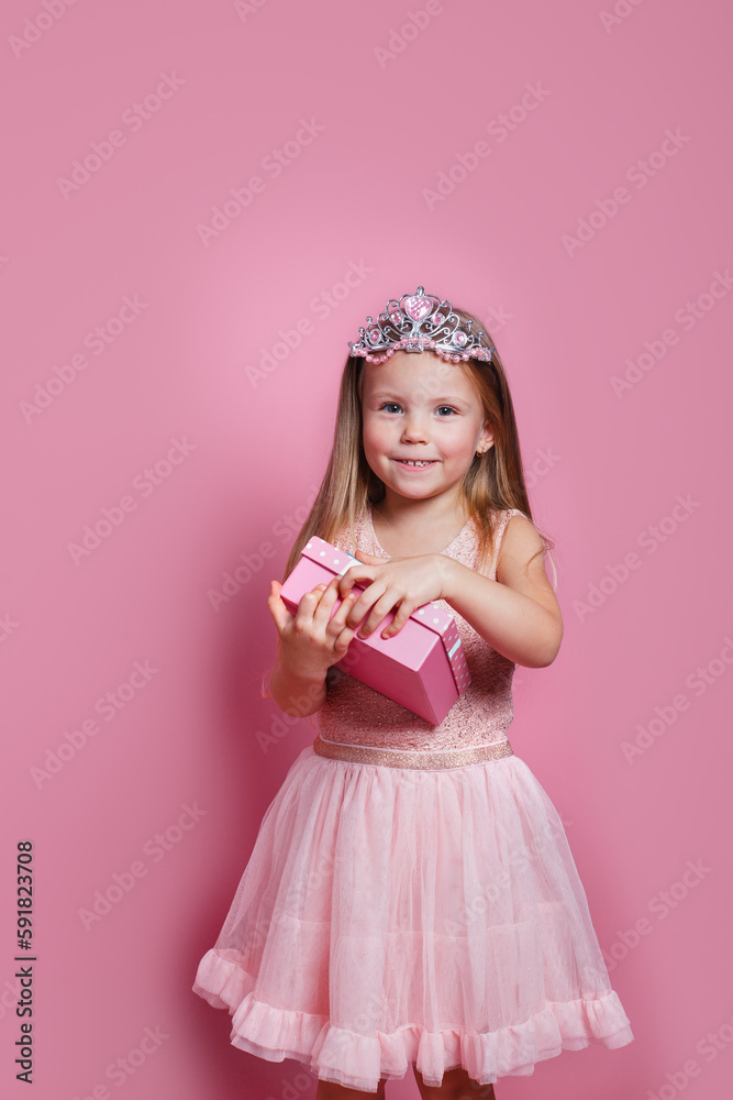 Cute sweet little princess toothy smile wearing pink dress opening present on pink background Cute sweet little princess toothy smile wearing pink dress opening present on pink background