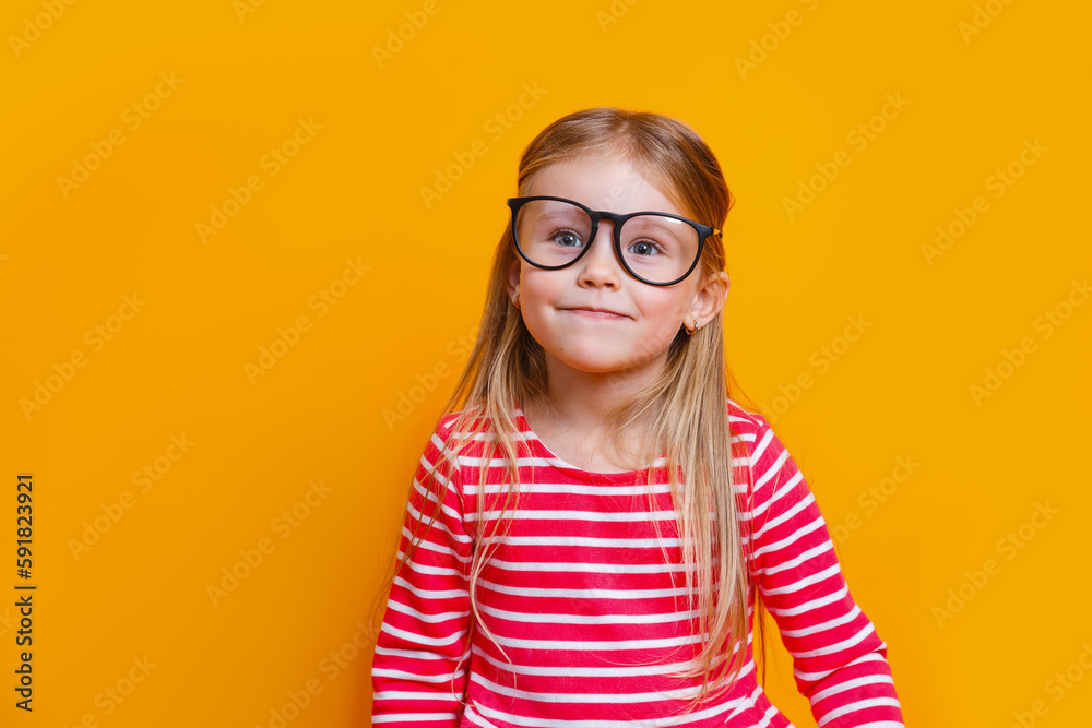 Close-up portrait of blond funny girl in red dress and glasses on yellow background
