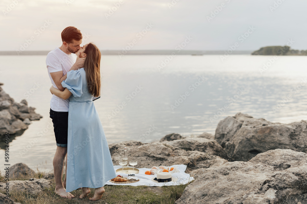 Happy gorgeous elegant couple kissing on summer picnic. They are relaxing together on a summer day. 