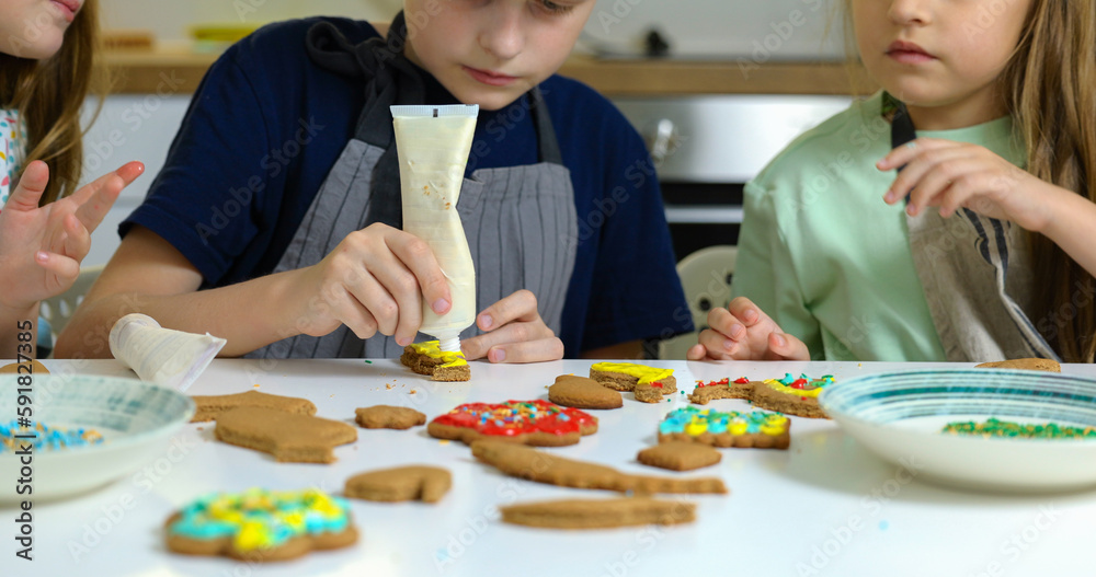 Little boy and girls decorate cookies on table with icing. Little boy and girls decorate cookies on table with icing.
