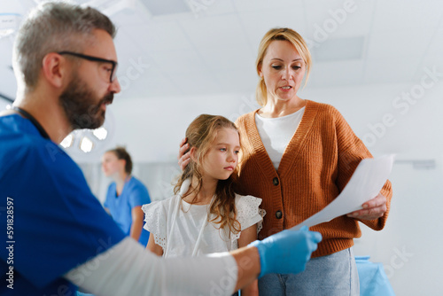 Doctor explaining something to mother of little girl with broken arm.