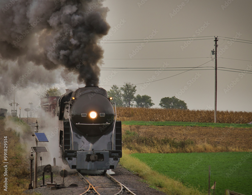 Antique restored steam freight train approaching with blowing smoke and steam