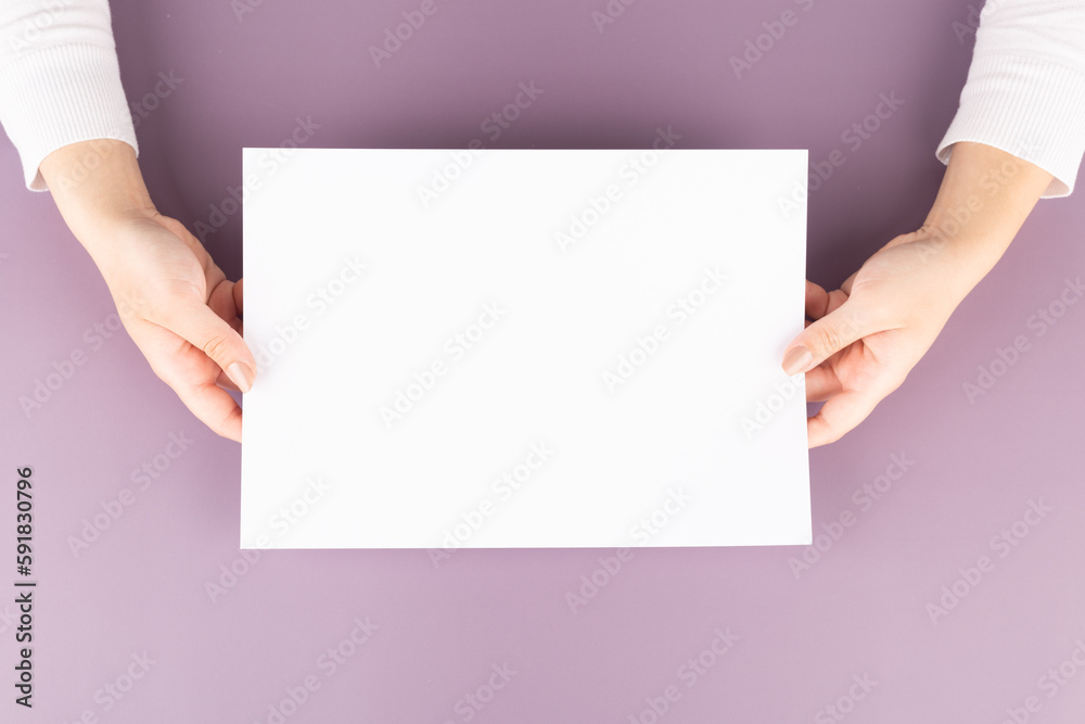 a woman holds a blank sheet of paper in her hands. Advertising space