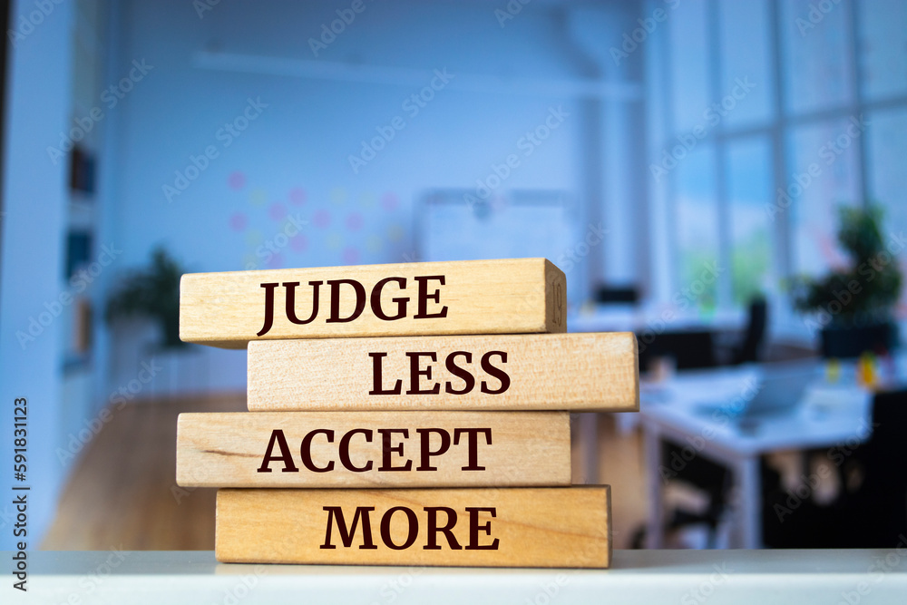 Wooden blocks with words 'JUDGE LESS ACCEPT MORE'.