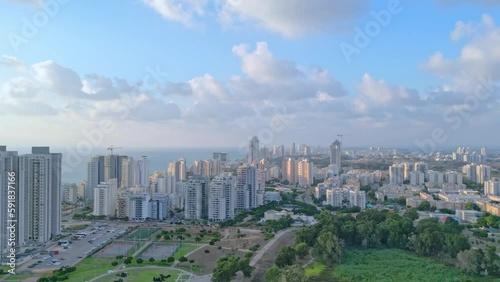 Netanya, Israel, September 3, 2022. Aerial view of the height of the city of Netanya at sunset. The sun illuminates the houses with golden rays. Blue sky with white clouds. High-quality 4k footage photo