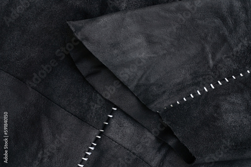 Sleeve detail of a black suede jacket with white contrast stitching
