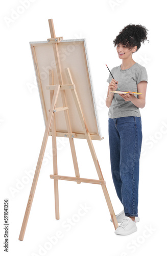 Young woman painting on easel with canvas against white background