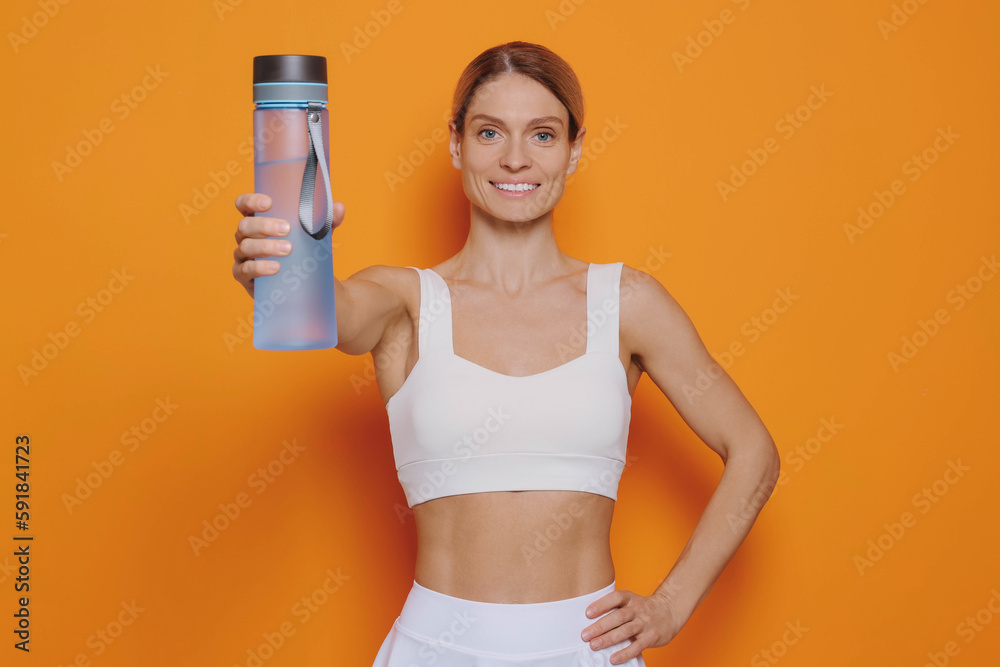 Sportswoman with bottle of water on orange background Sportswoman with bottle of water on orange background