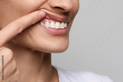 Woman showing healthy gums on light background, closeup. Space for text