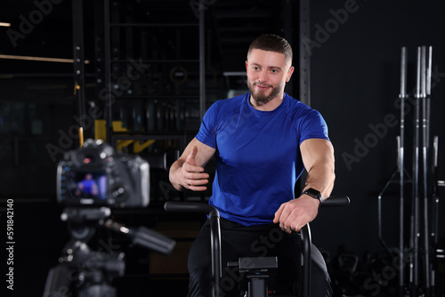 Man recording workout on camera at gym. Online fitness trainer