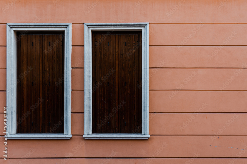 White windows covered with wooden boards of a pink building White windows covered with wooden boards of a pink building