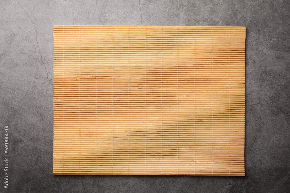 Naklejka premium Bamboo mat on grey table, top view. Space for text
