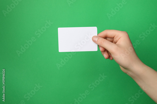 Woman holding blank gift card on green background, closeup