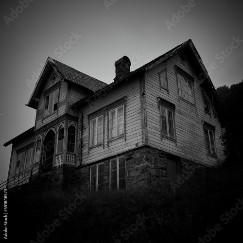 Fototapeta Naklejka Na Ścianę i Meble -  Low angle grayscale of an enormous abandoned ghost house with broken windows in Norway