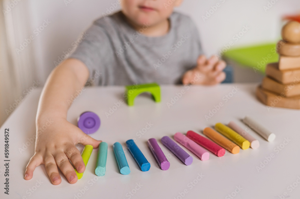A three-year-old boy plays with crayons, plasticine and a construction set. The concept of early development and sensory perception. Finger games in kindergarten A three-year-old boy plays with crayons, plasticine and a construction set. The concept of early development and sensory perception. Finger games in kindergarten