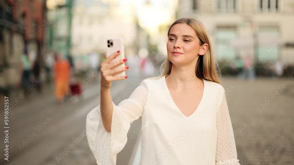 Beautiful Happy Young Blonde Woman Making a Video call Smiling Talking Walking Relaxed on the City Background Beautiful Happy Young Blonde Woman Making a Video call Smiling Talking Walking Relaxed on the City Background