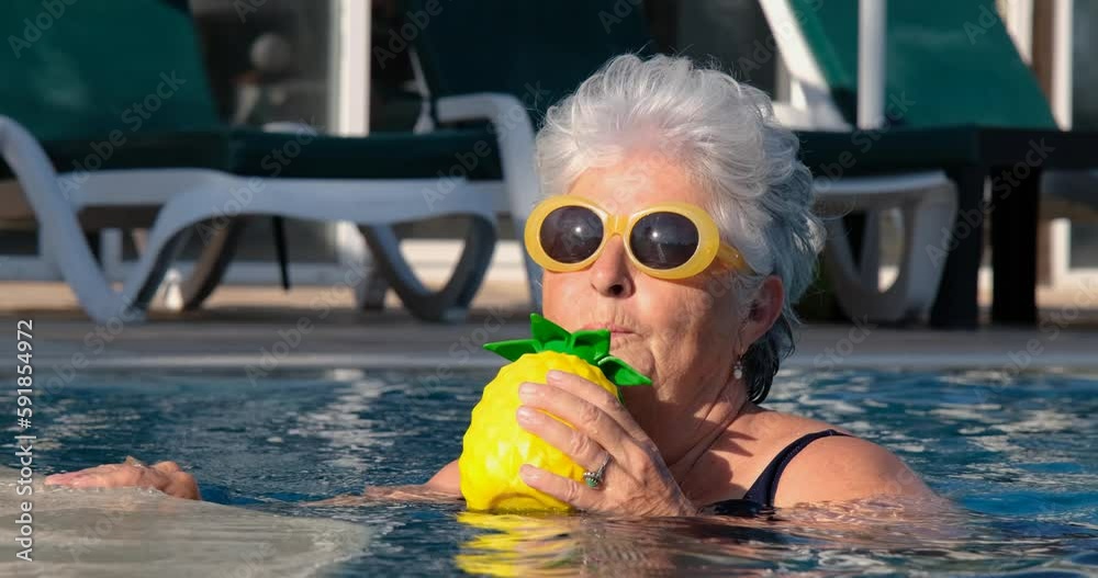 Beautiful elderly lady with fashionable sunglasses in swimming pool, enjoying cocktail. Looking at camera. Tropical summer vacation travel destination. Positive lifestyle background. Set of 13 files.