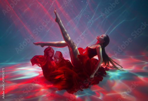 Fotografiet Fantasy woman drowning at bottom of ocean sea beauty ballerina girl swimming posing underwater sexy long legs red dress floating soars