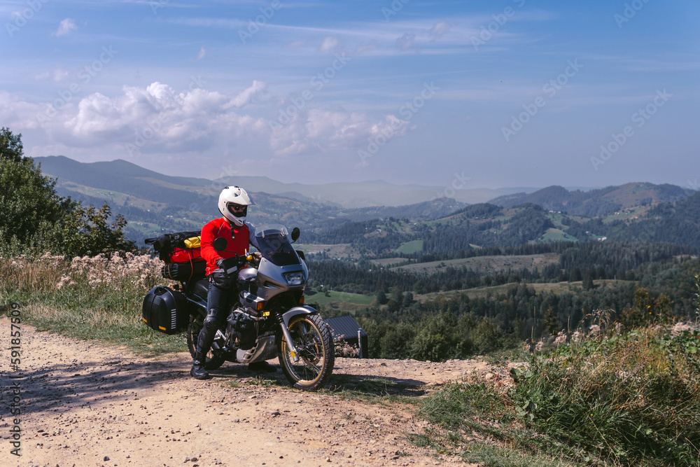 Motorbiker travelling, summer day, motorcycle off road, the driver with adventure, touring motorbike with side bags, extreme tourism, sport weather clothes, Carpathians mountains Ukraine