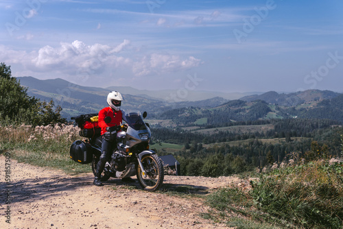 Motorbiker travelling  summer day  motorcycle off road  the driver with adventure  touring motorbike with side bags  extreme tourism  sport weather clothes  Carpathians mountains Ukraine
