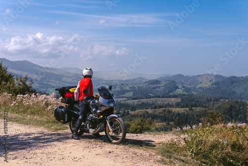 Motorbiker travelling, summer day, motorcycle off road, the driver with adventure, touring motorbike with side bags, extreme tourism, copy space, mountains