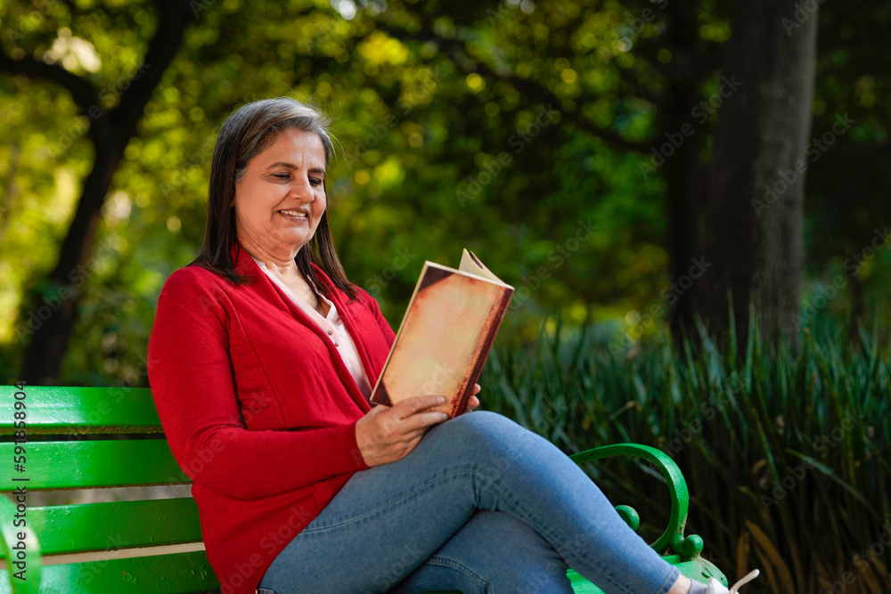 Obraz premium Indian senior woman reading book at park.