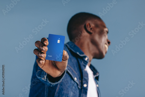 Happy black man holds his credit card towards the camera, recommending the use of mobile payments and electronic banking