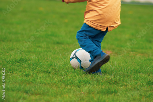 Child playing with a soccer ball on a green field